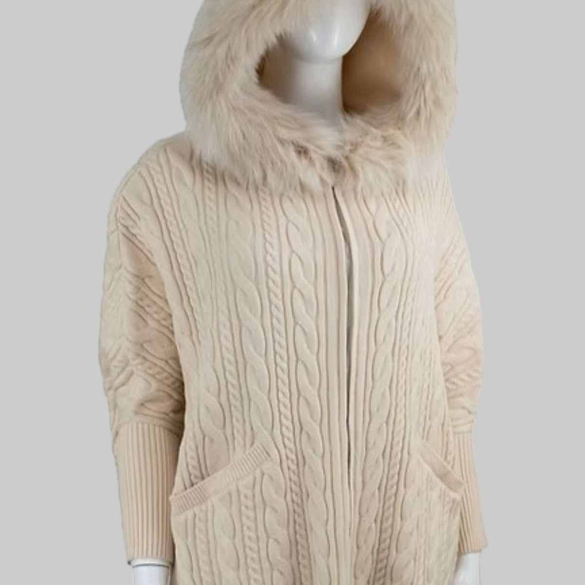 Beige cable knit hoodie with fur hood on a mannequin against a white background