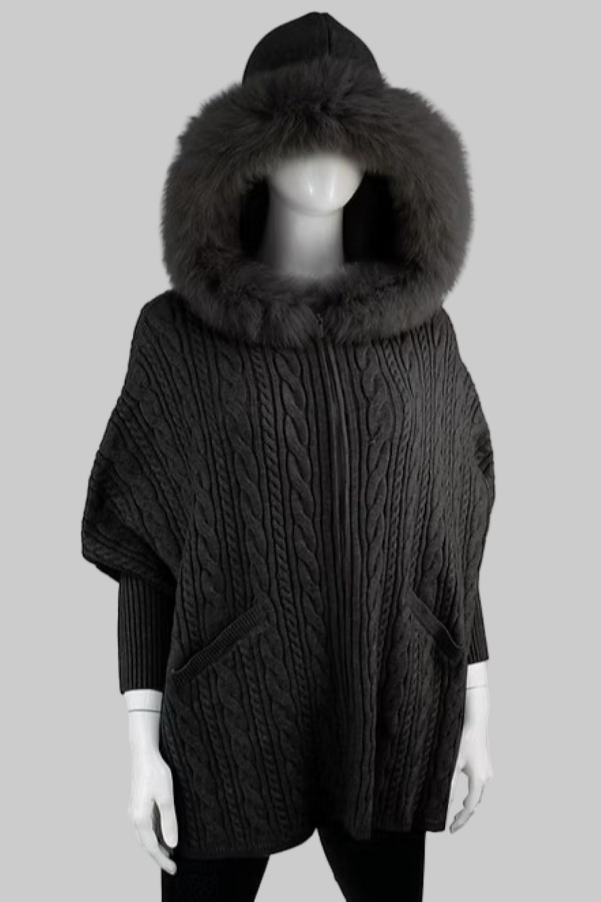 Dark gray cable knit poncho with a large fur hood on a mannequin against a white background