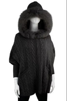 Dark gray cable knit poncho with a large fur hood on a mannequin against a white background